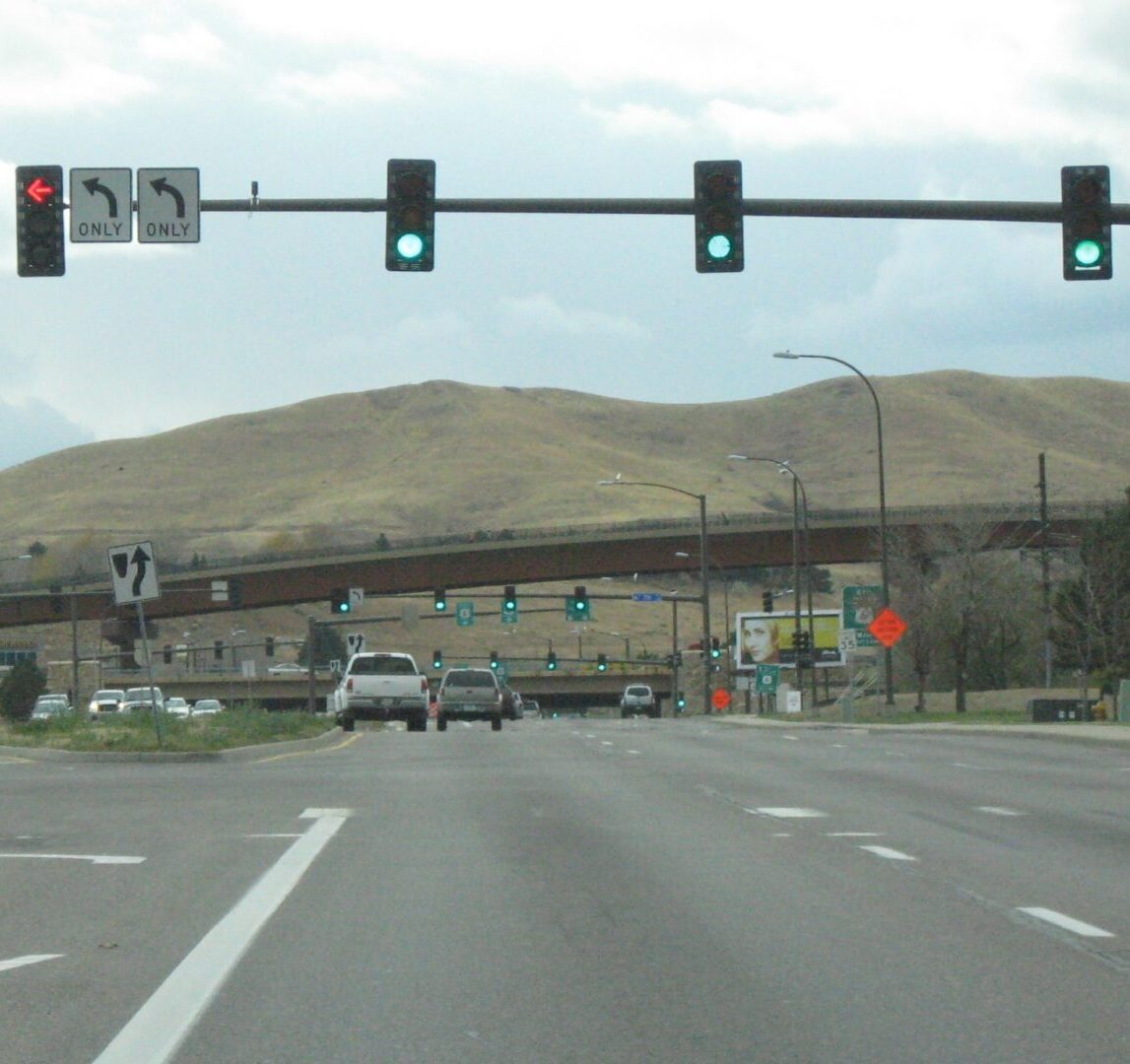 Traffic lights and signs with cars on road.