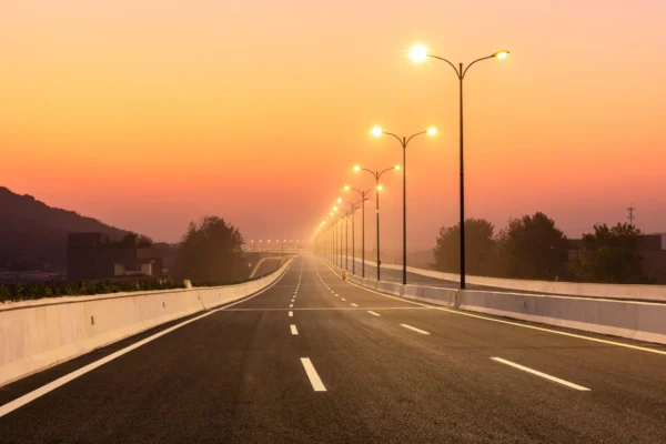 Empty highway at sunrise with streetlights.